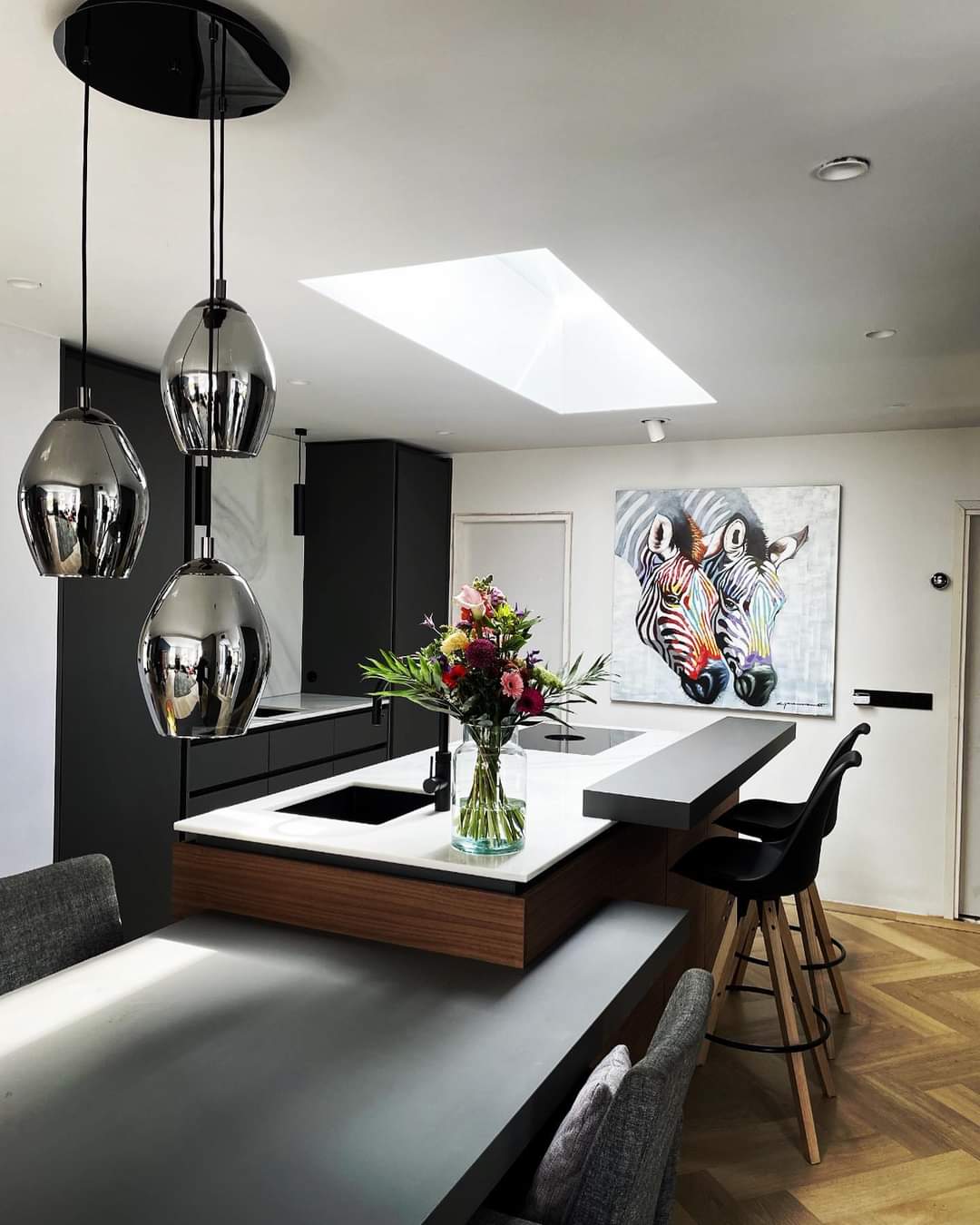 Moderne zwarte keuken met wit marmeren eiland en designlampen