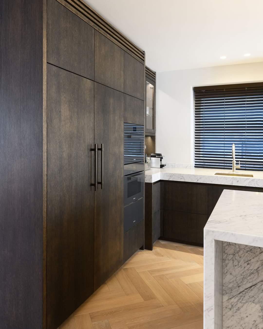 Maatwerk keuken in donker hout met marmeren aanrecht en inbouwapparatuur